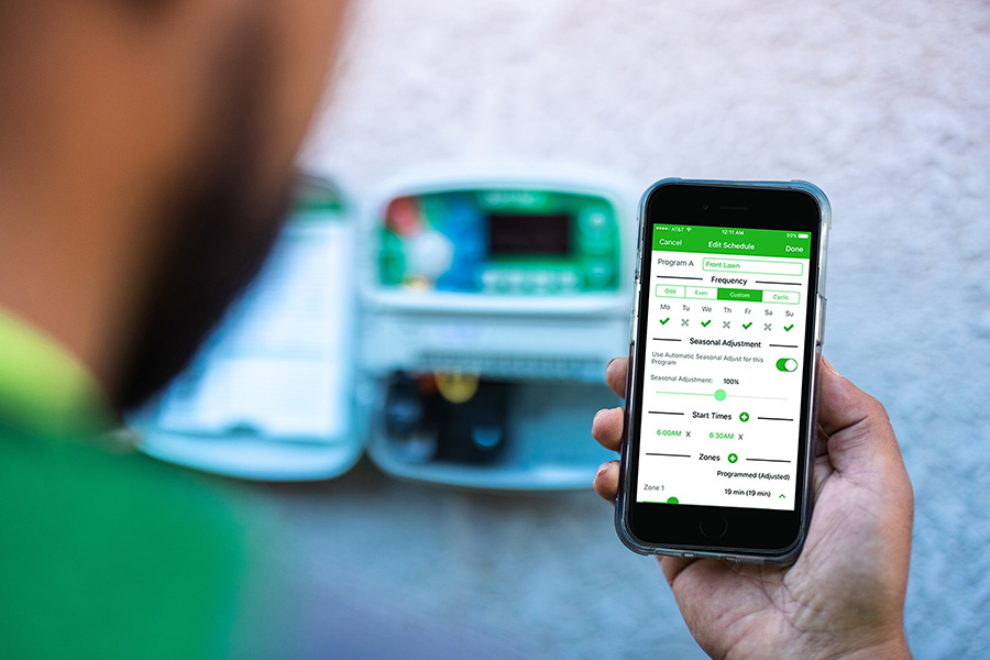 Wi-Fi Controlled Systems Worker using a mobile phone to remotely check on irrigation system